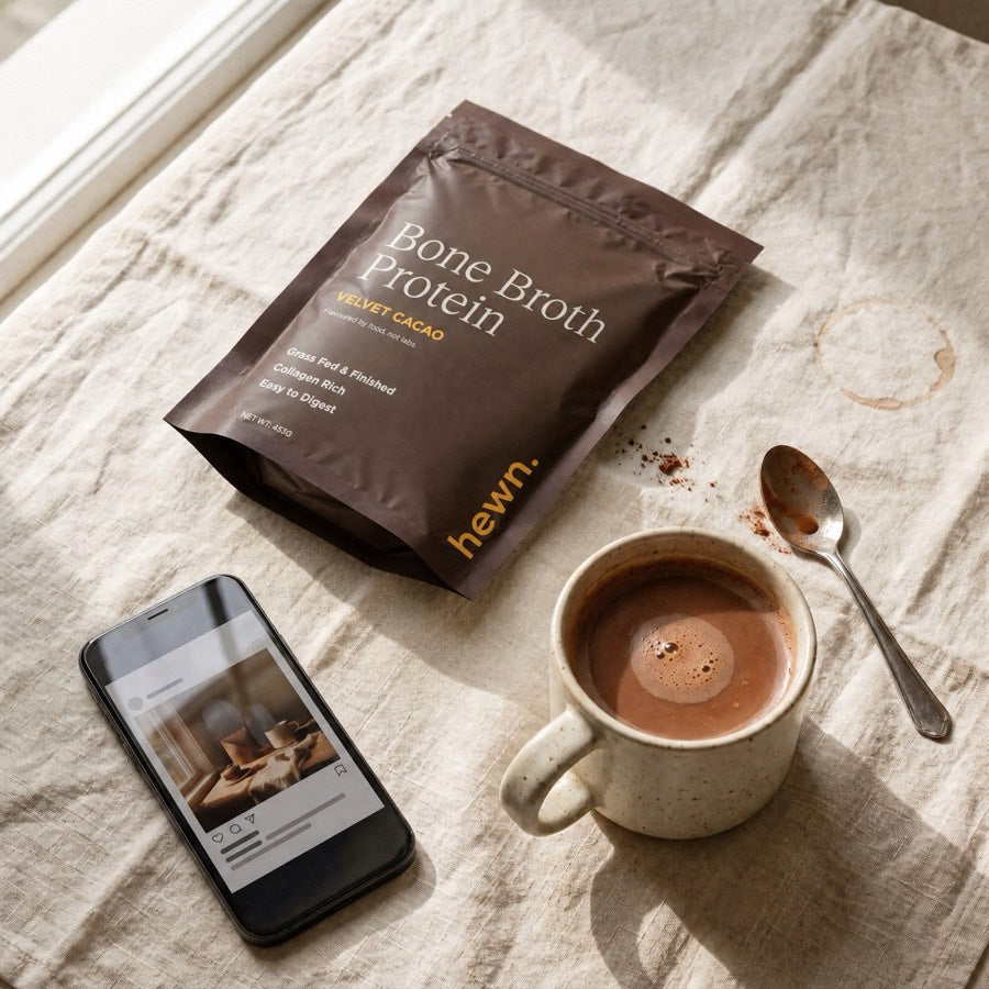 A bag of hewn beside a filled mug and a phone showing a social post