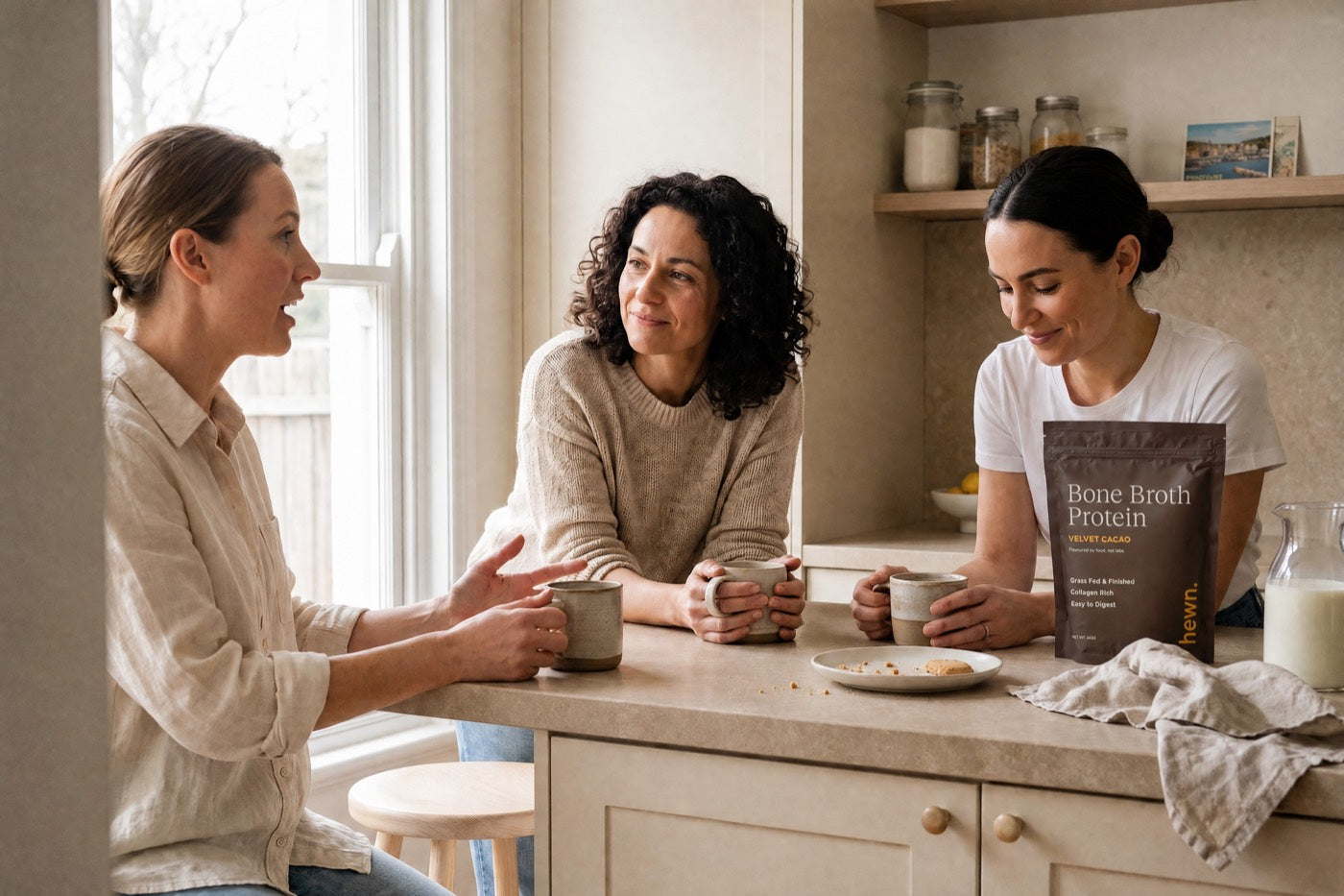 Three women talking over coffee with a bag of hewn on the bench